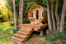 Load image into Gallery viewer, Dundalk Leisurecraft Canadian Timber Tranquility Barrel Sauna with Front Porch, placed outside near trees in a backyard facing left with beautiful view of the backyard
