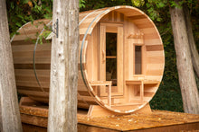 Load image into Gallery viewer, Dundalk Leisurecraft Canadian Timber Tranquility Barrel Sauna with Front Porch, placed outside near trees in a backyard facing right
