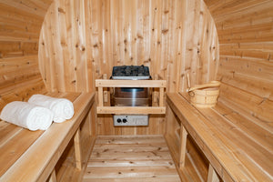 Inside the Dundalk Leisurecraft Canadian Timber Serenity Barrel Sauna with heater, towels, and water bucket with ladle